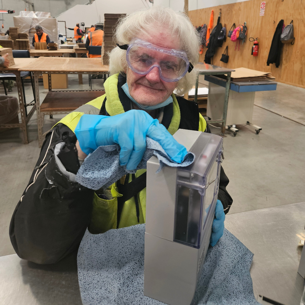 old man with safety goggles wiping an electricity meter with a blue cloth